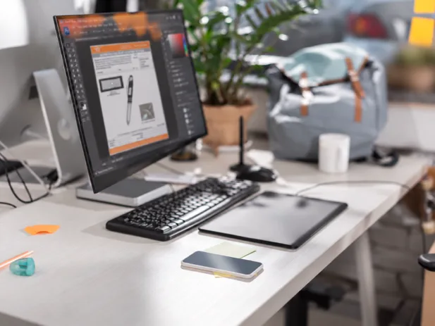 A graphic designer's desk with product artwork open on screen